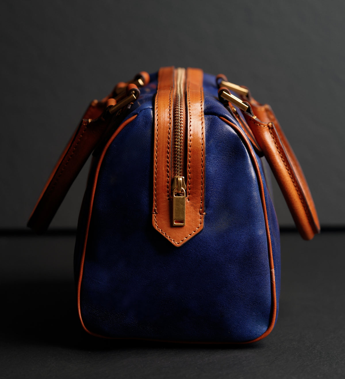 Cucitura laterale e tiretto zip in ottone sul bauletto Little Dorrit blu, dettaglio ravvicinato