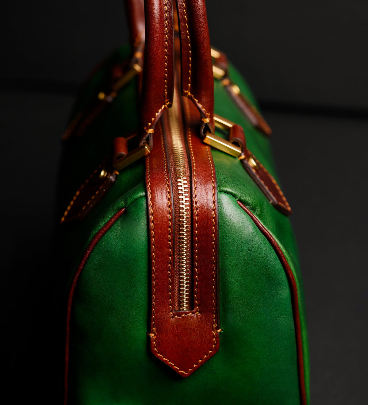 Dettaglio ravvicinato della linguetta in pelle marrone e della ferramenta in ottone sul bauletto Little Dorrit verde