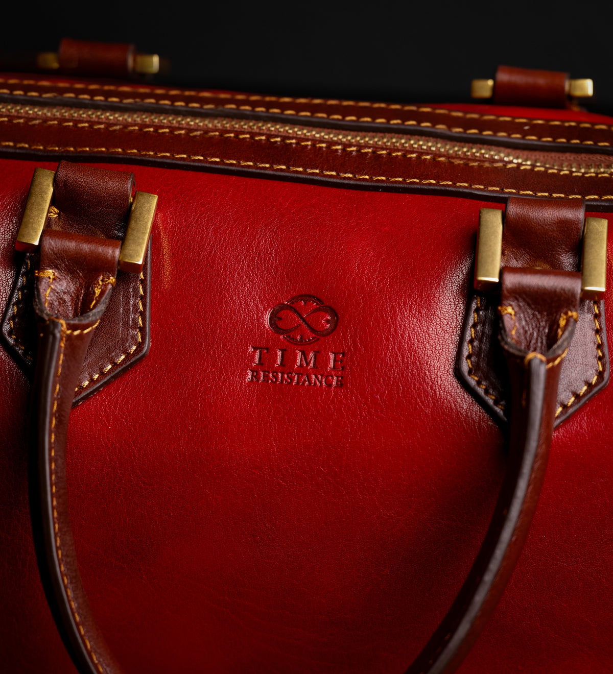 Dettaglio ravvicinato della ferramenta in ottone e del logo impresso sul bauletto Little Dorrit rosso